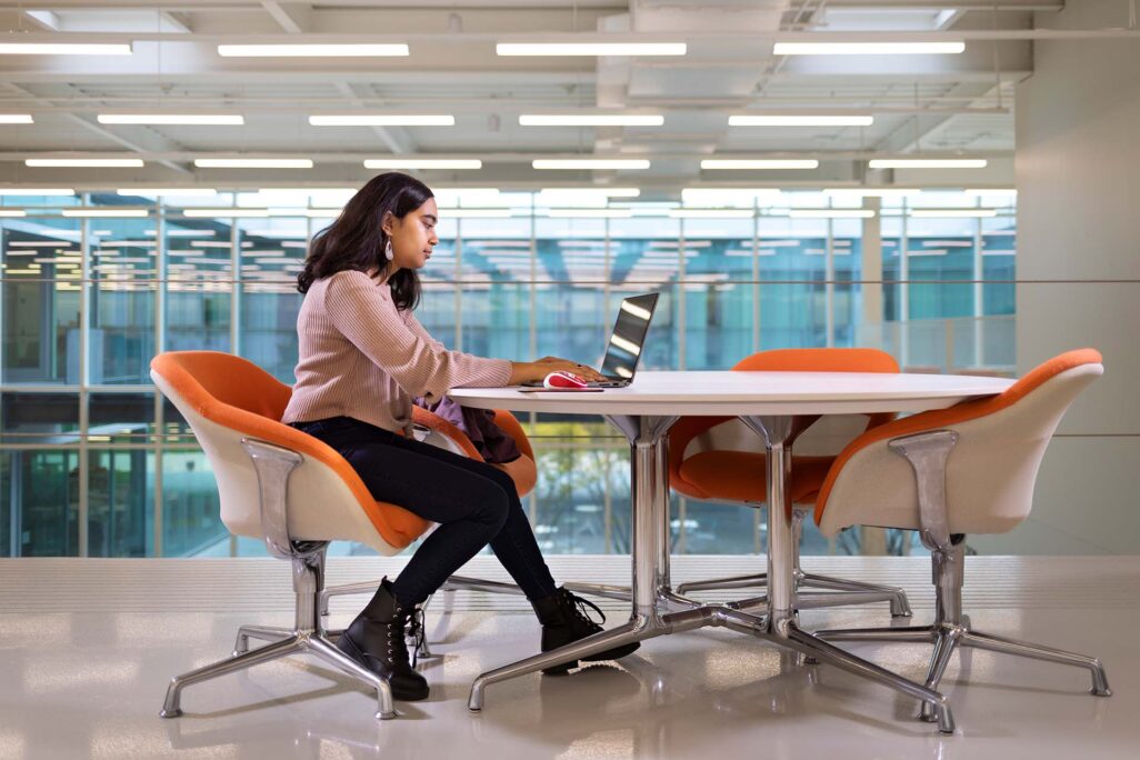 iit_landing-page_business_image-1 Business student alone at table in commons room at Illinois Tech