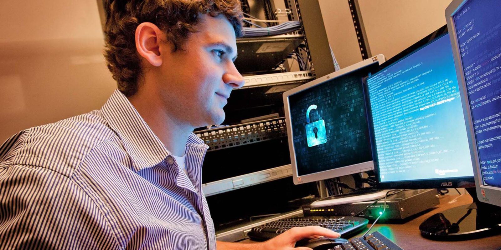 iit_landing-page_cybersecurity_hero man at desk with several monitors open reviewing code