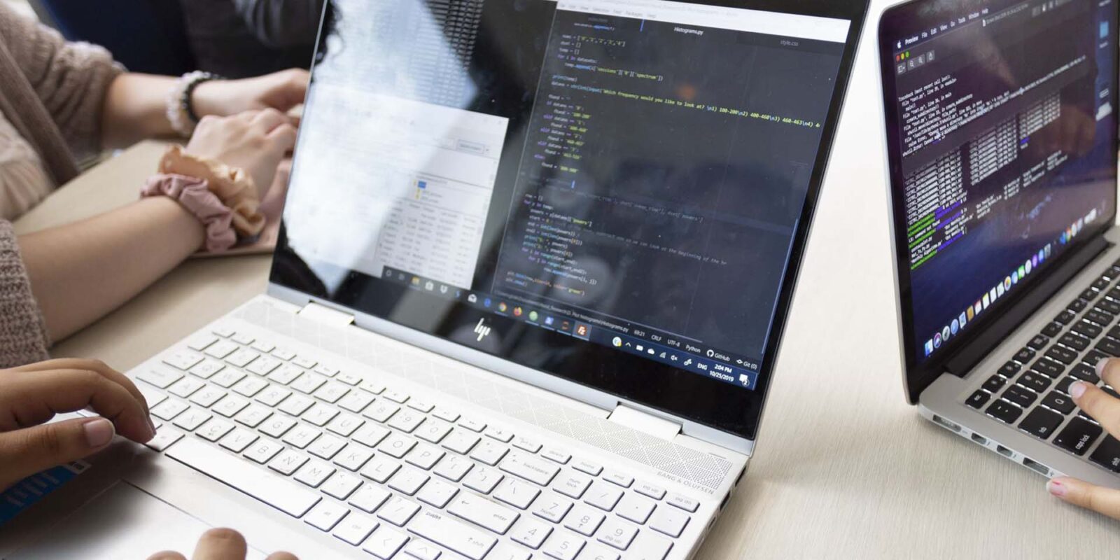 group of cybersecurity students at laptops reviewing code