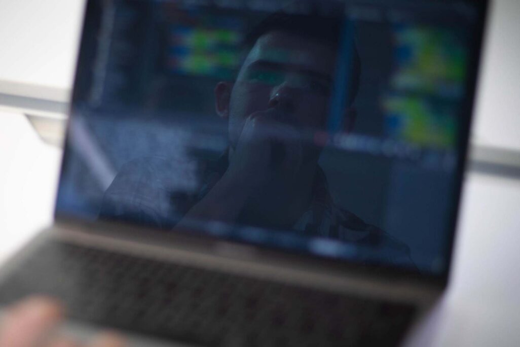 mans reflection in face of laptop